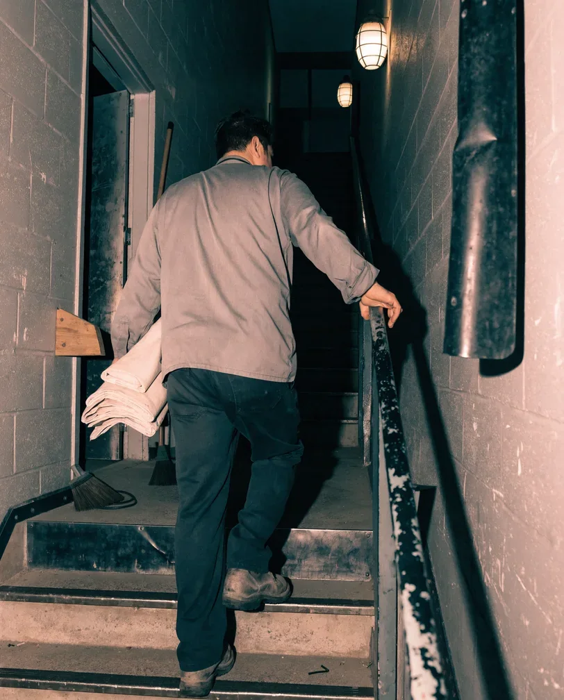 A worker carrying folded linens up a back of house stairwell